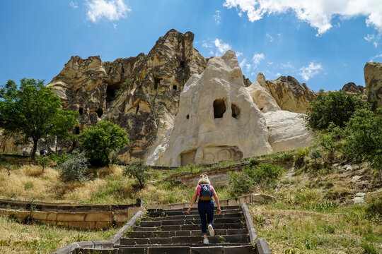 Cappadocia. A tourist, girl climbing the stairs to see ancient ruins of churches carved into the sandy rocks, selective focus
