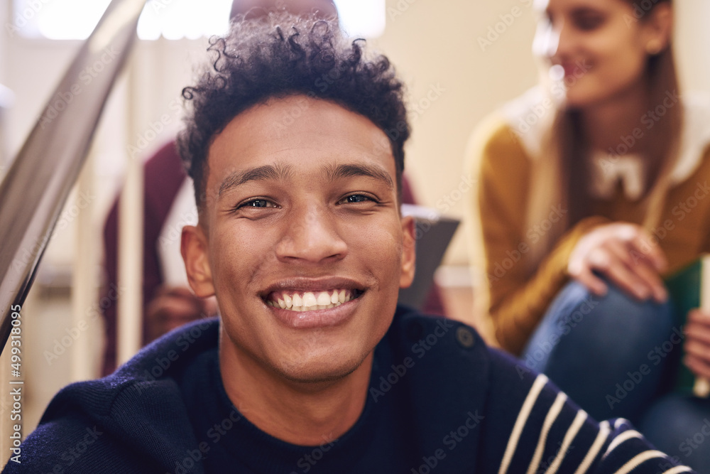 Wall mural University life is great. Cropped portrait of a handsome young male student sitting on a campus staircase with his friends.