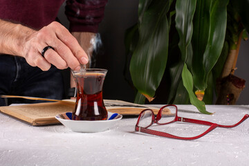 Man reading a book and a cup of hot turkish tea on the table