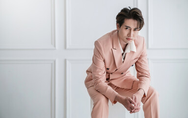 Portrait of Korean asian handsome smile friendly Business model man in pink suit sitting , business man smart with success, manager or executive with leadership office fashion workspace.