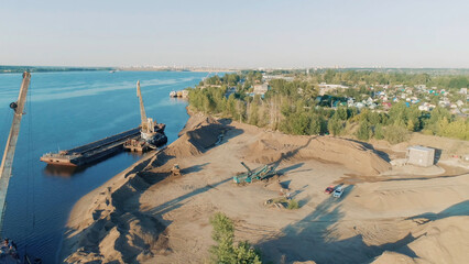 Construction cranes and trucks on shore. Scene. Top view of clearing of construction site on lake shore. Start of construction on lake shore on sunny day © Media Whale Stock