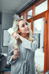 Going through her haircare routine. Shot of a young woman brushing her hair at home.