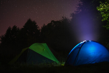 Camping tents amid bright night stars away from cities in the wild. Adventure traveling lifestyle. Concept wanderlust. Active weekend vacations wild nature outdoor.
