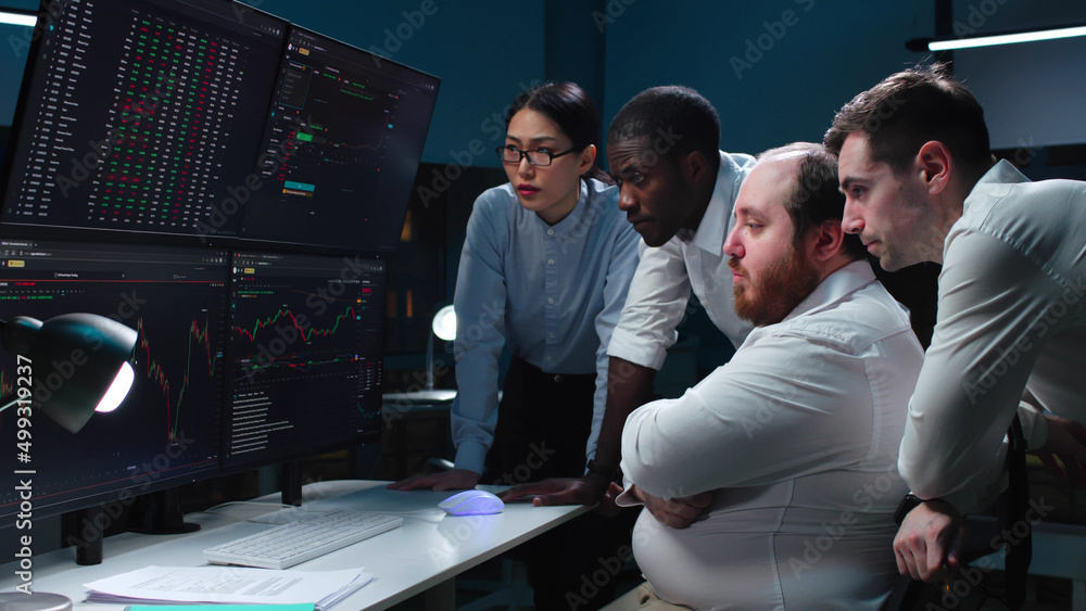 Wall mural team of traders working at monitor computer and browsing online in trading office