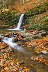 Leaf fall on  beautiful mountain cascade waterfall with lake at autumn. Carpathians. Ukraine.