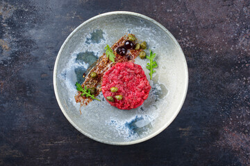 Modern style gourmet tartar raw from beef filet with capers and amarena cherry served with truffle...