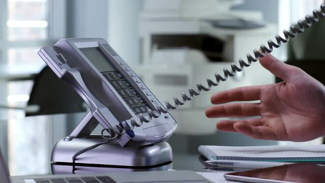 Close up of office employee answer telephone on desk