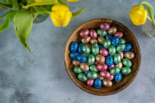 Wooden bowl with pastel colored easter-eggs on gray background