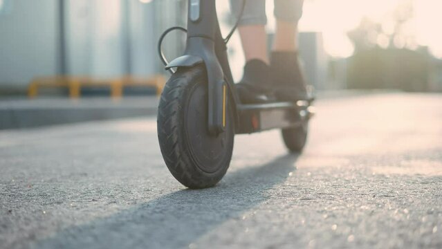 electric scooter. child riding electric a scooter close-up sun glare. road transport in city concept. speed sport energy concept. wheel close-up sun drive bicycle. eco future