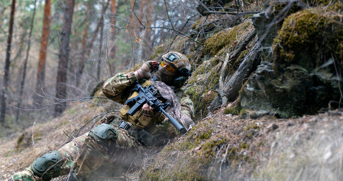 A special forces soldier during a clash in the forest. He calls his group's support on the walkie-talkie. Concept of modern military operations.