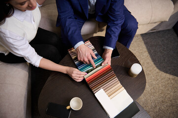 Focus on samples of colored fabrics for upholstered furniture. Top view of couple choosing color...