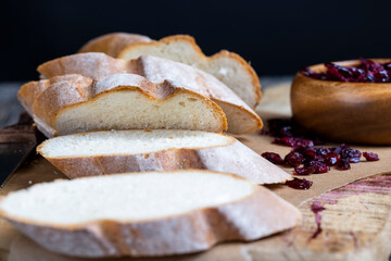 cranberry and sliced soft fresh baguette on a cutting board and table