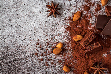 almonds, dark chocolate, cocoa powder, anise stars on a gray neutral concrete background