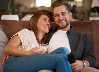 Television is the most common and best form of entertainment. Cropped shot of a young couple relaxing with popcorn on the sofa at home.