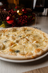 Four cheese pizza quattro formaggi with glass of wine on background with new year decorations.