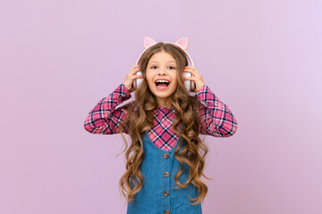 A girl in a denim skirt and a plaid jacket listens to music with headphones. The child is happy with the new headphones.