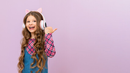 A girl in a denim skirt and a plaid jacket listens to music with headphones. The child is happy with the new headphones.