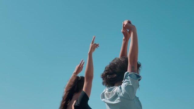 Girls standing with open arms against the blue sky. Best friends spend summer time together. The girls are happy and enjoy life. The road by car to the sea. Friendship and love forever. The beauty of