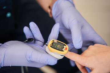 Doctor puts a pulse oximeter on the child's finger to measure the oxygen saturation