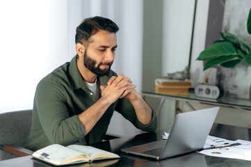 Pensive focused Indian or Arabian successful man, broker, manager, sits at a desk in the office,...