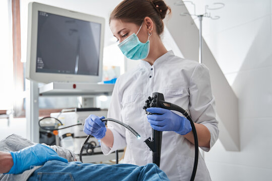 Female doctor wearing protective mask holding endoscope during gastroscopy