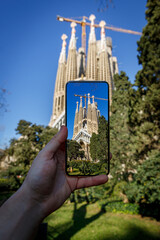 Taking a photo of Sagrada Familia with a mobile phone camera in Barcelona, Spain.