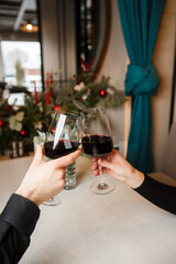 love, dating and people concept - close up of couple clinking wine glasses. Close up front view on male and female caucasian hands holding glasses of red wine toasting.