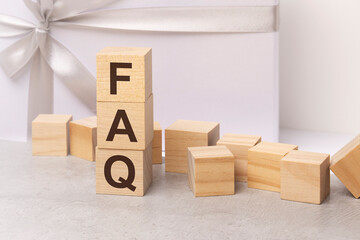 faq - letters on wooden cubes. concept on white gift box background