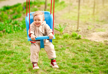 Little girl rides on a swing and smiles