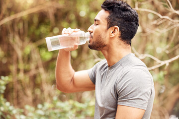 Fuel your fitness with hydration. Shot of a fit young man drinking water after his workout in nature.