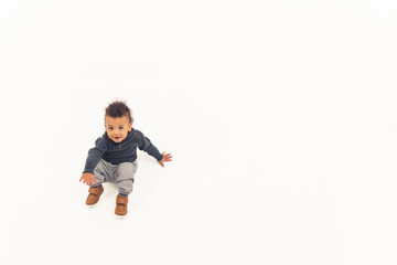 Innocent curious biracial baby boy standing up over white background. Copy space. High quality photo