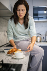 Portrait domestic woman in pajamas and towel on hairs posing with cup of fresh coffee at kitchen