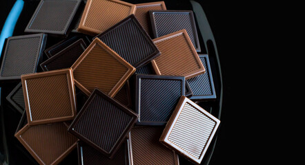 Milky and bitter square shape chocolate Madlen,designed on black plate with copy space.The Sugar...