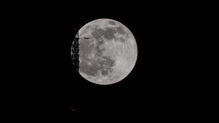 Obraz premium super full moon behind the Stuttgart TV Tower - the antenna is touching the moon. An airplane is flying across