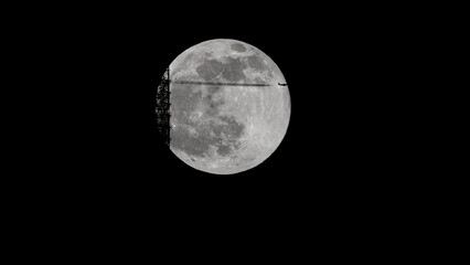 super full moon behind the Stuttgart TV Tower - the antenna is touching the moon. An airplane is...
