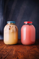 Two jars of homemade kvass, wheat or rye bread and hibiscus kvas, on wooden dark rustic background. National slavic summer tasty beverage