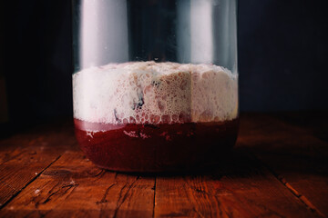 Jar of rye bread, hibiscus homemade kvass, kvas in process of making. High foam from sugar and yeast, rustic background. Slavic drink, closeup - obrazy, fototapety, plakaty