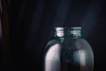 Upper part of a glass transparent jar on dark background, closeup shot, copy space