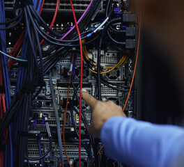 Sometimes its just a matter of connecting point A to point B. Cropped shot of an unrecognizable male IT support agent working in a dark network server room.