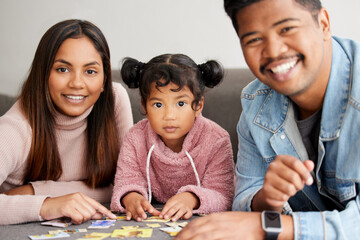 Puzzles are important for mental development. Shot of young parents helping their daughter build a...