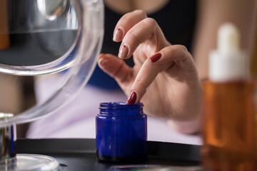 Girl sitting at the sofa and taking her cream from the jar while having morning routine