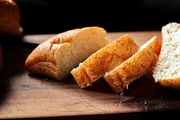 Freshly baked bread being sliced on a wooden cutting board.