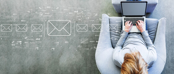 Email concept with man using a laptop in a modern gray chair