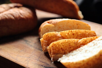 Freshly baked bread being sliced on a wooden cutting board.