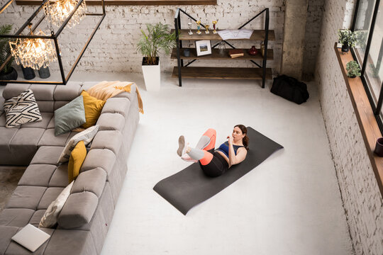 Caucasian handicapped woman laying at the floor and raising up her legs while training