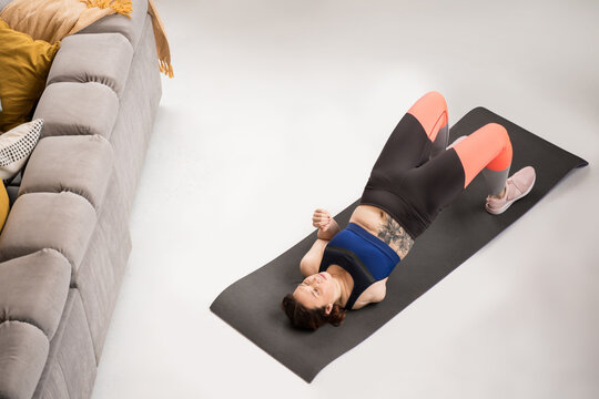 Handicapped woman laying at the floor and training her press muscles at the yoga mat