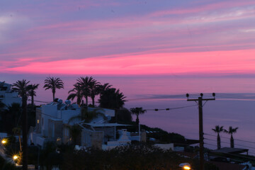 Palm trees beaches and seas on the south cyprus coast as sunset against a red, orange and yellow sky
