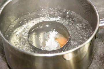 Poaching fresh eggs in a pan of water in an authentic kitchen environment. - obrazy, fototapety, plakaty
