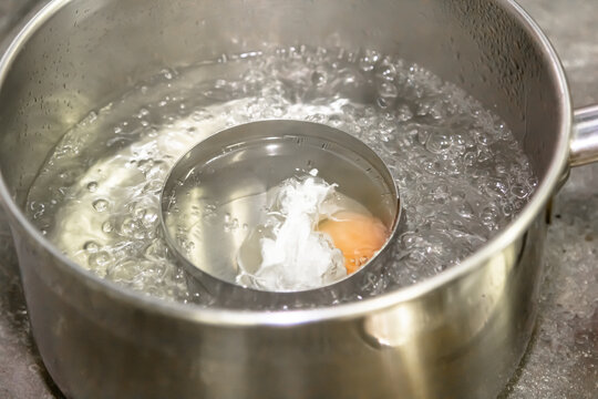 Poaching fresh eggs in a pan of water in an authentic kitchen environment.