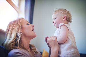 Can you say mama. Shot of an adorable baby girl bonding with her mother at home.